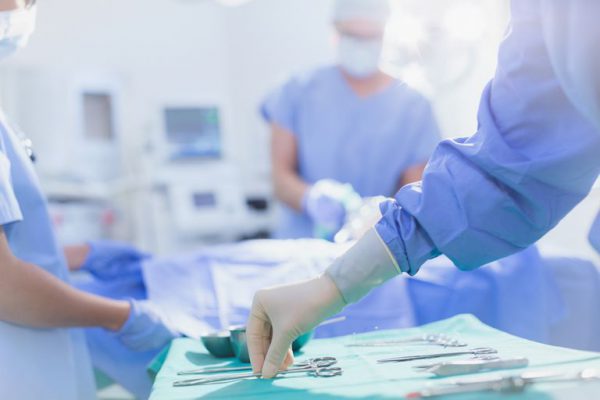 surgeon in rubber gloves reaching for surgical scissors on tray in operating room 909193162 5b99aa5f4cedfd0025741906 600x400 - Explore -